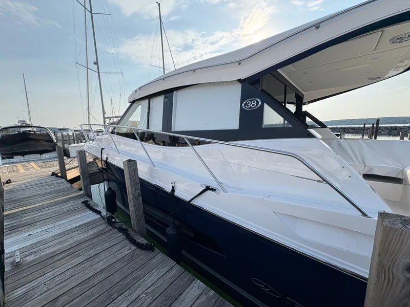 Slide: The Image of The 2024 Regal 38 Grande Coupe is docked at a wooden pier. It features a sleek design. - 3