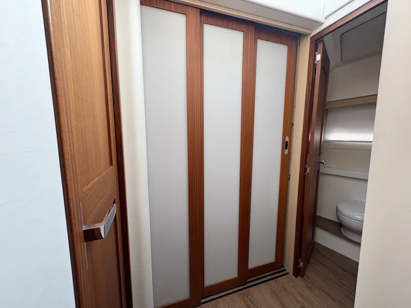 Slide: The Image of The cabin of the 2024 Regal 38 Grande Coupe features a wooden door and a bathroom with a toilet. - 44