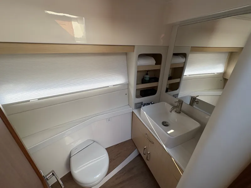 Slide: The Image of The image shows a modern boat bathroom with a toilet, sink, and mirror. - 46