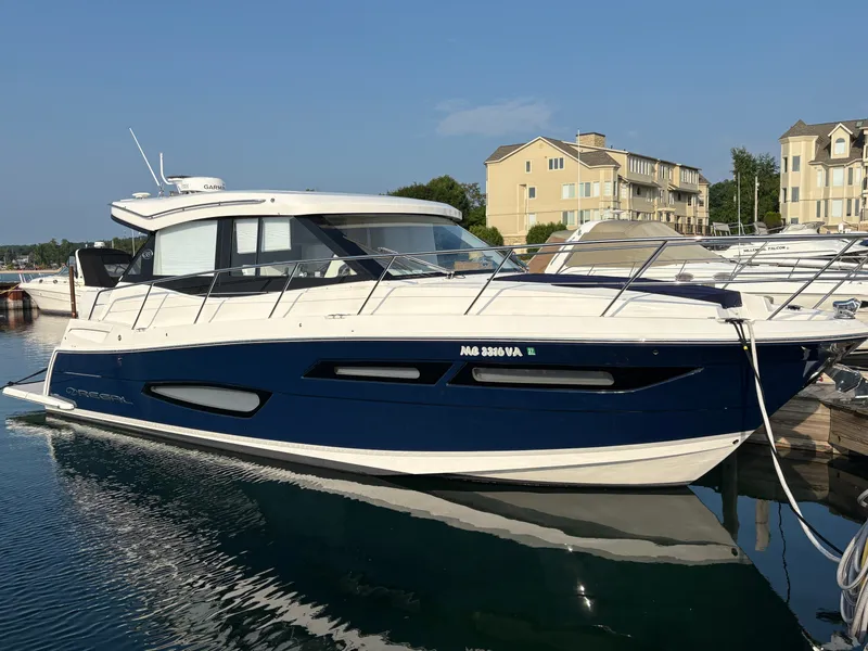 The Image of The 2024 Regal 38 Grande Coupe is docked on a sunny day with modern buildings in the background. - 0