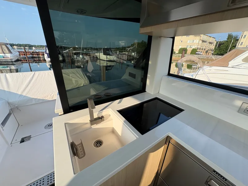 Slide: The Image of The 2024 Regal 38 Grande Coupe's kitchen with sink and cooktop, docked at a marina. - 10