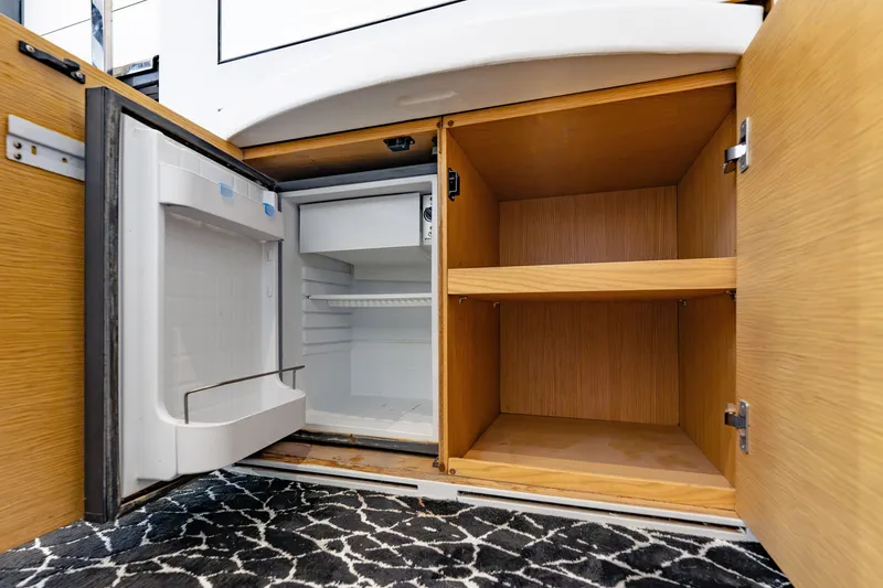Slide: The Image of Open wooden cabinets and mini fridge inside a 2010 Pershing 80 yacht. - 57