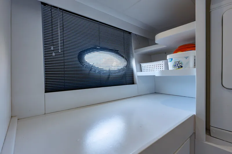 Slide: The Image of Laundry area on a 2010 Pershing 80 yacht with storage shelves and porthole window. - 90