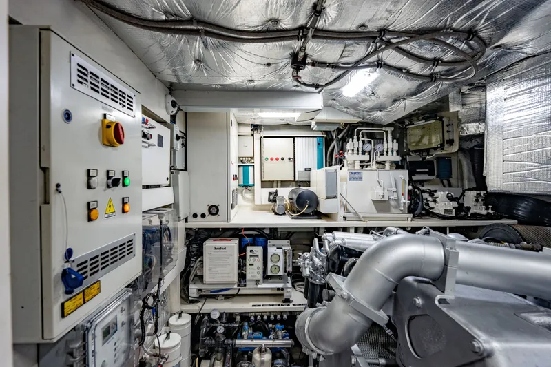 Slide: The Image of Engine room of a 2010 Pershing 80 yacht, featuring control panels and machinery. - 98