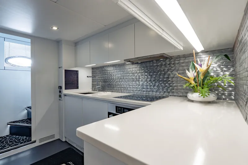 Slide: The Image of Modern kitchen interior on 2010 Pershing 80 yacht, featuring sleek design and floral arrangement. - 80