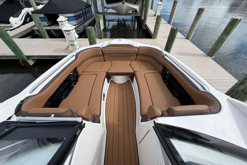 Slide: The Image of 2025 Yamaha Boats 275SD interior with luxurious brown seating and sleek design at a dock. - 26
