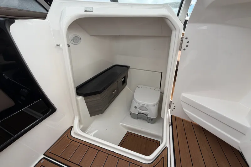 Slide: The Image of 2025 Yamaha Boats 275SD interior cabin with compact toilet and storage area. - 30