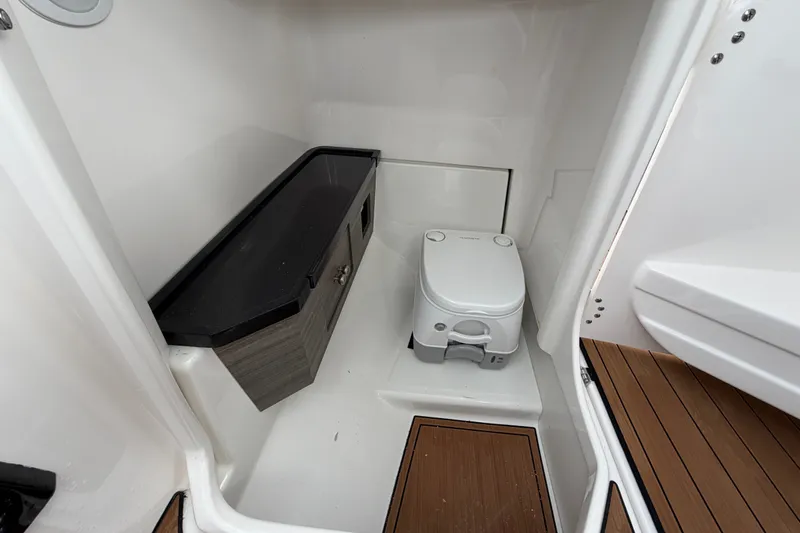 Slide: The Image of 2025 Yamaha Boats 275SD interior bathroom with compact toilet and storage cabinet. - 31