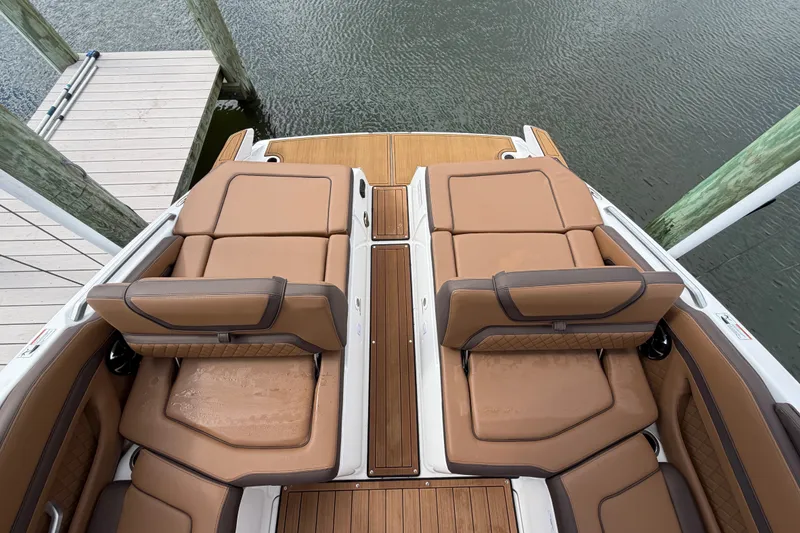 Slide: The Image of 2025 Yamaha Boats 275SD with luxurious tan seating and wooden deck, docked by the water. - 12