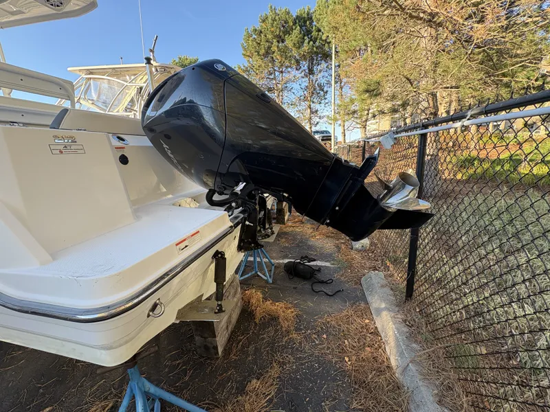 Slide: The Image of A 2019 Blackfin 212 CC with an outboard motor, propped up in a fenced area. - 27