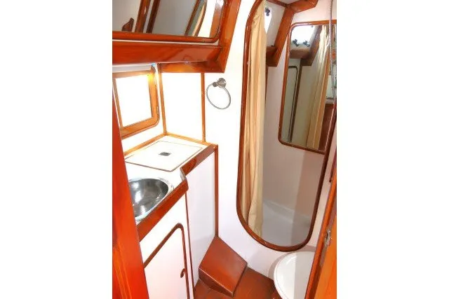 Slide: The Image of 1986 Tayana 52 Center Cockpit bathroom with sink, shower, and wooden accents. - 45
