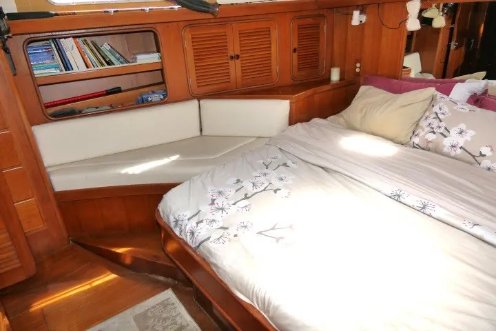 Slide: The Image of Cozy 1986 Tayana 52 Center Cockpit interior with bed, bookshelves, and wooden cabinetry. - 38