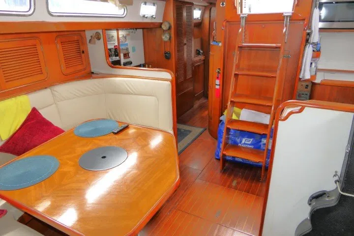 Slide: The Image of Interior of 1986 Tayana 52 Center Cockpit yacht with wooden dining area and ladder. - 7