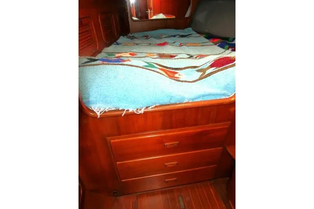 Slide: The Image of 1986 Tayana 52 Center Cockpit interior with wooden drawers and colorful bedspread. - 23