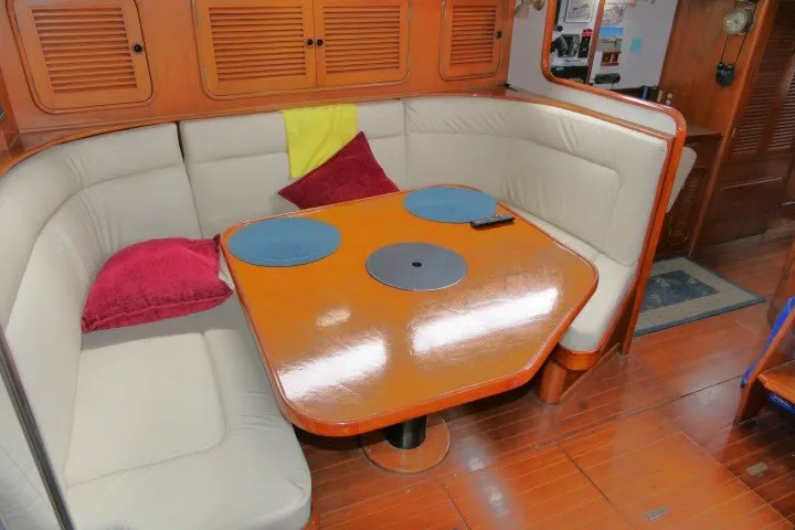 Slide: The Image of Cozy dining area in 1986 Tayana 52 Center Cockpit yacht with cushioned seating and wooden table. - 6
