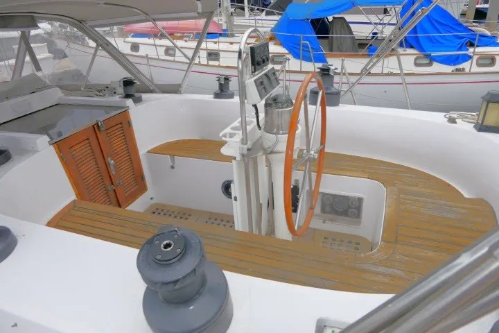 Slide: The Image of 1986 Tayana 52 Center Cockpit with wooden deck and steering wheel in marina setting. - 59