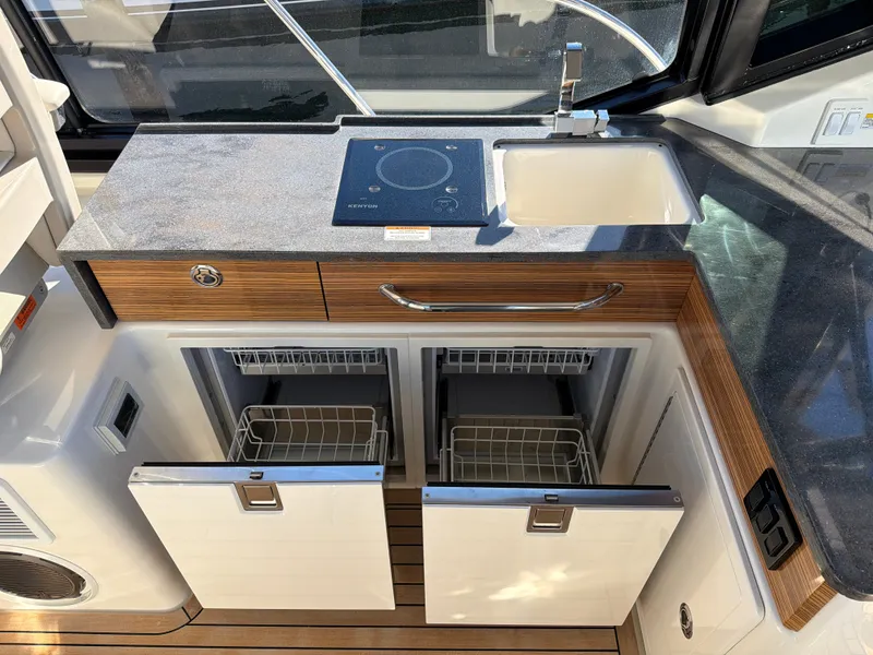 Slide: The Image of The 2024 Boston Whaler 405 Conquest galley features a cooktop, sink, and cabinetry. - 50