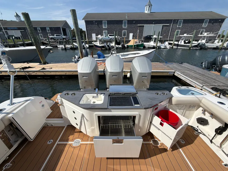 Slide: The Image of The image shows the stern of a 2024 Boston Whaler 405 Conquest. It features three engines and is docked. - 21