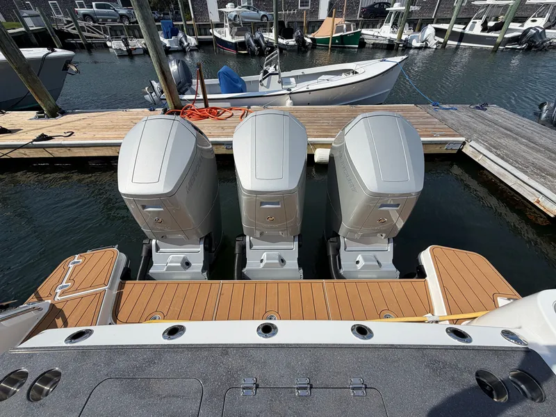 Slide: The Image of Three powerful outboard engines on a Boston Whaler 405 Conquest, docked at a wooden pier. - 19