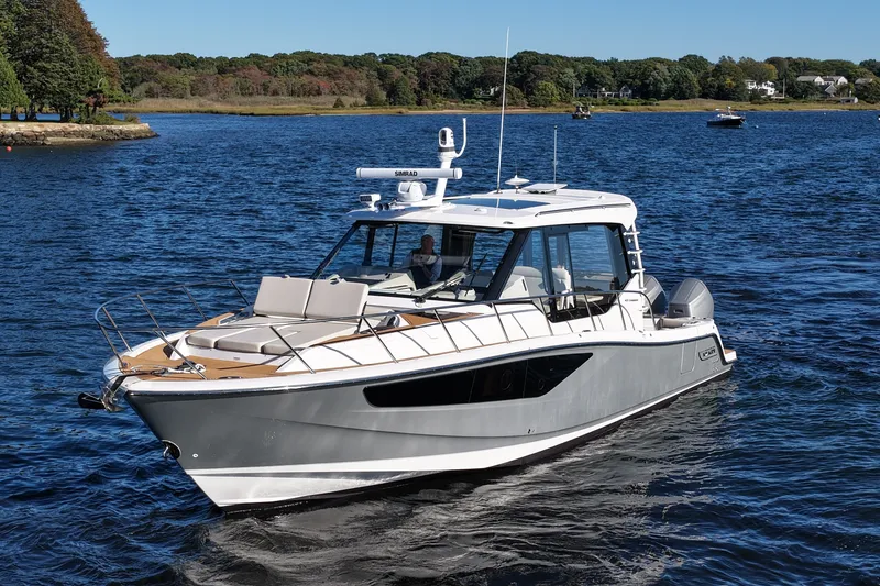 Slide: The Image of A sleek motorboat with a gray hull and white superstructure cruising on calm waters. - 15