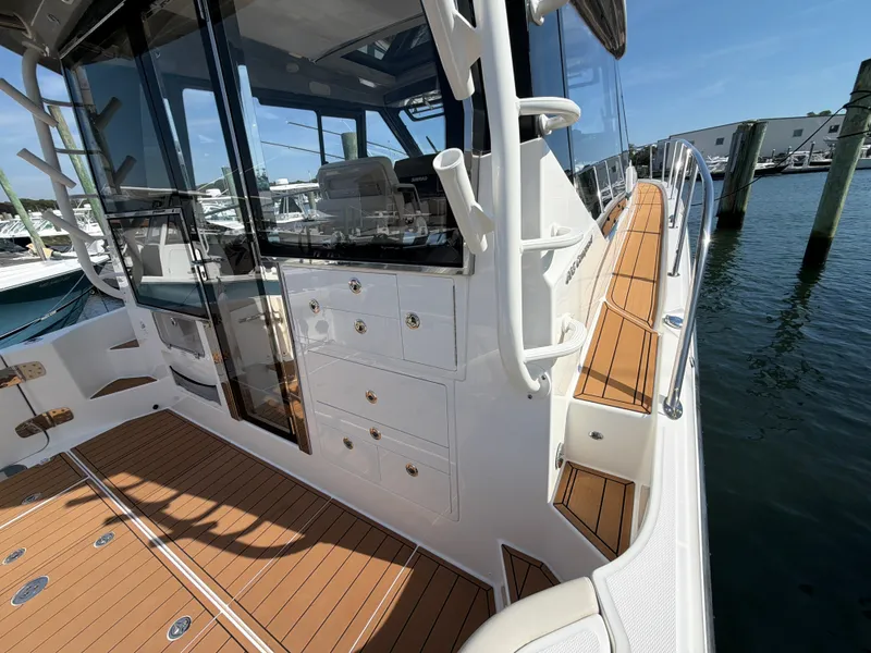 Slide: The Image of The image shows the deck of a 2024 Boston Whaler 405 Conquest with wood flooring and white details. - 35