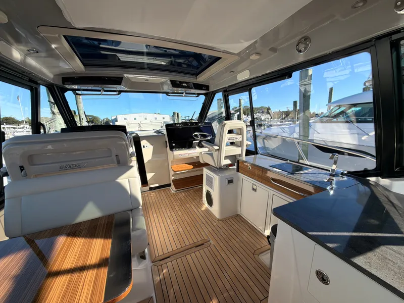 Slide: The Image of Interior of a modern yacht with wooden flooring, white seating, and large windows overlooking the marina. - 48