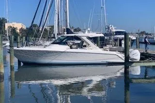 The Image of 2021 Tiara Sport 38 LS boat docked in a marina, reflecting on calm water. - 0