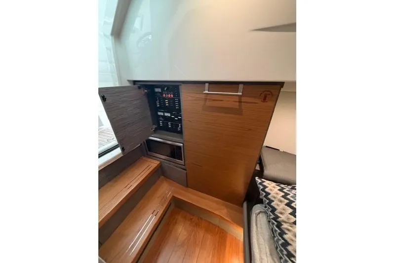 Slide: The Image of Interior of 2021 Tiara Sport 38 LS boat, featuring control panel and wooden cabinetry. - 26