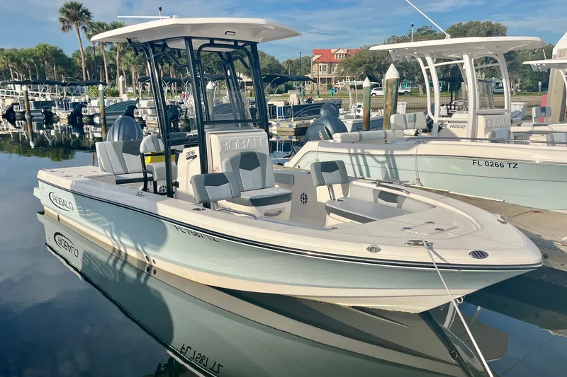 The Image of 2025 Robalo 226 Cayman boat docked at marina, reflecting on calm water. - 1