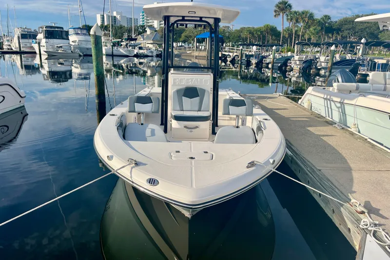 Slide: The Image of 2025 Robalo 226 Cayman boat docked at a marina, surrounded by other vessels. - 2