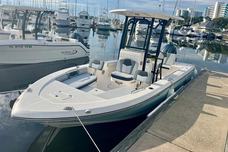 Slide: The Image of 2025 Robalo 226 Cayman boat docked at marina with other vessels in background. - 3
