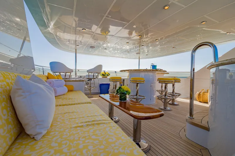 Slide: The Image of Luxurious 2002 Christensen Trideck yacht deck with yellow seating, bar stools, and ocean view. - 47