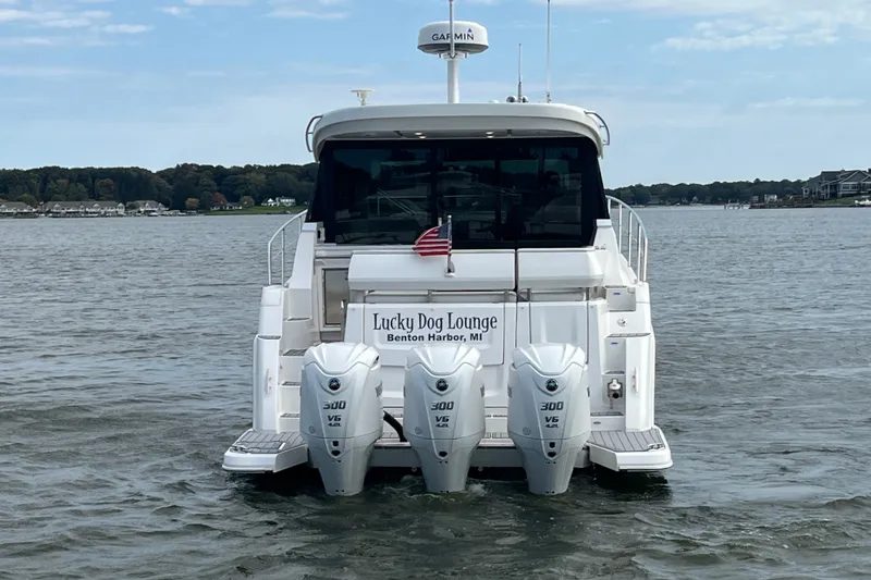 Slide: The Image of 2023 Regal 38 XO yacht with triple outboard engines on a calm lake. - 2