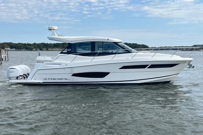 Slide: The Image of 2023 Regal 38 XO yacht cruising on a calm lake under a partly cloudy sky. - 37