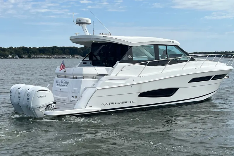 Slide: The Image of 2023 Regal 38 XO yacht cruising on a lake with triple Yamaha engines. - 35