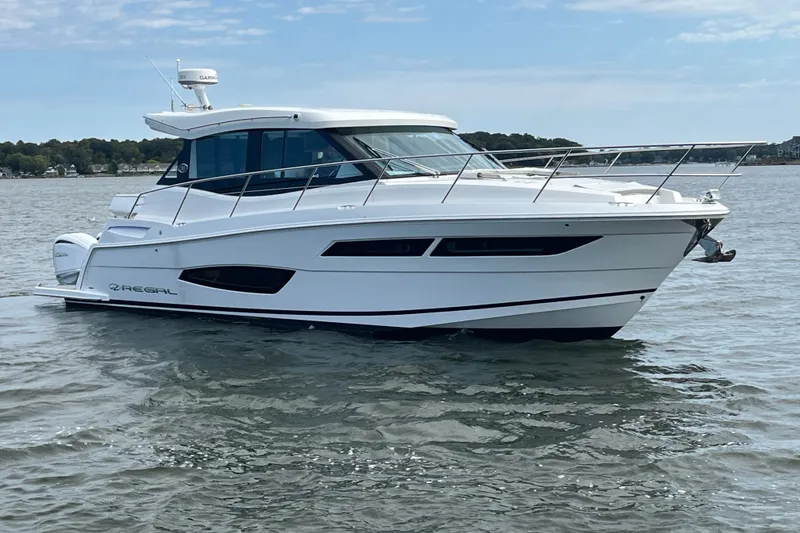 Slide: The Image of 2023 Regal 38 XO yacht cruising on calm waters under a clear sky. - 3