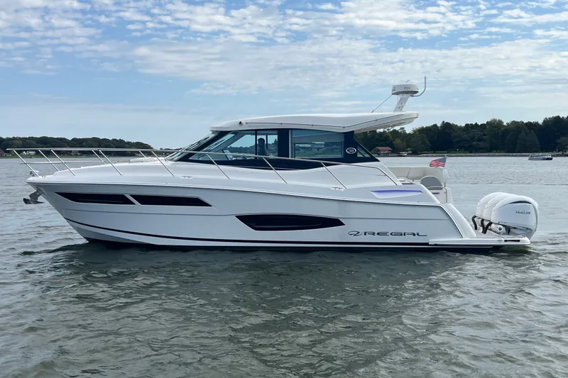Slide: The Image of 2023 Regal 38 XO yacht cruising on a calm lake under a partly cloudy sky. - 1