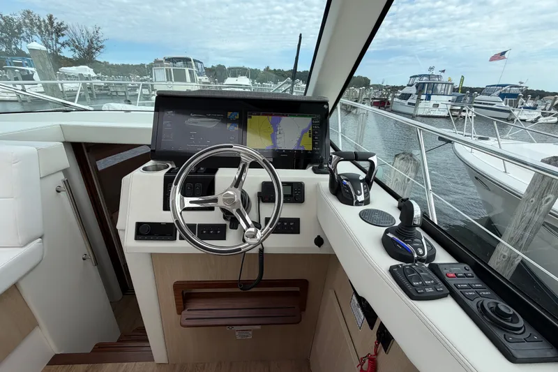 Slide: The Image of Helm of 2023 Regal 38 XO yacht with modern navigation controls and scenic marina view. - 16