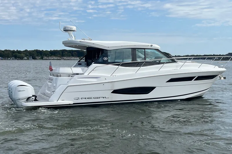 Slide: The Image of 2023 Regal 38 XO yacht cruising on a calm lake under a partly cloudy sky. - 36