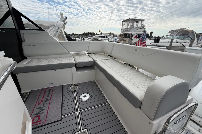 Slide: The Image of Luxurious seating on 2023 Regal 38 XO yacht, docked with other boats under a cloudy sky. - 6