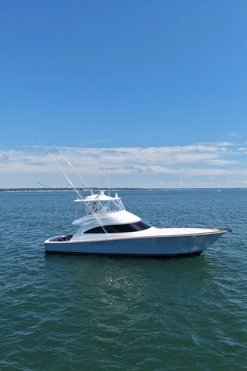 Slide: The Image of A sleek, modern boat with a white hull and flybridge on calm water under a blue sky. - 7