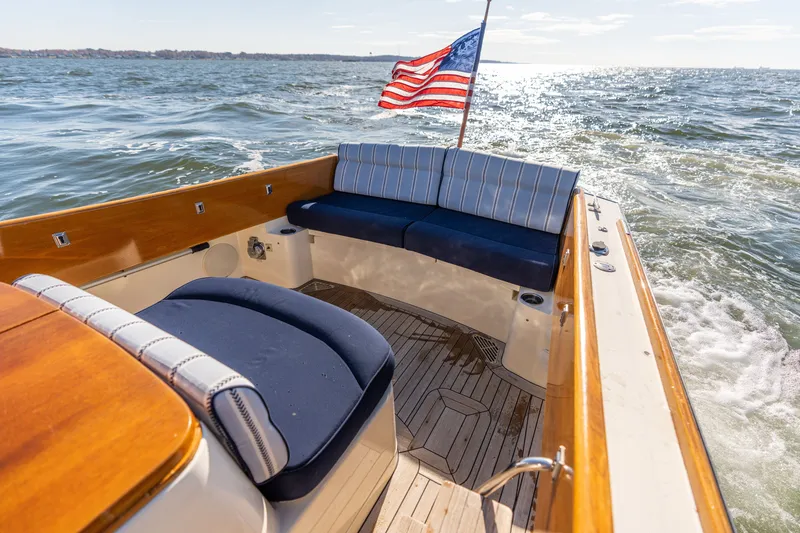 Slide: The Image of Hinckley Picnic Boat 36 EP 2006 cruising with American flag, featuring elegant seating and wooden deck. - 19