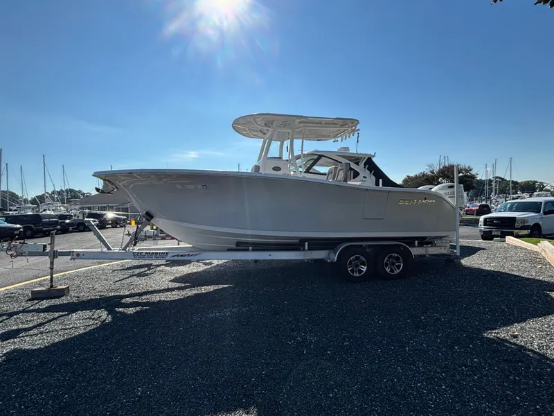 Slide: The Image of A 2021 Sea Pro 259 DLX boat on a trailer, parked on a gravel lot under sunny skies. - 3