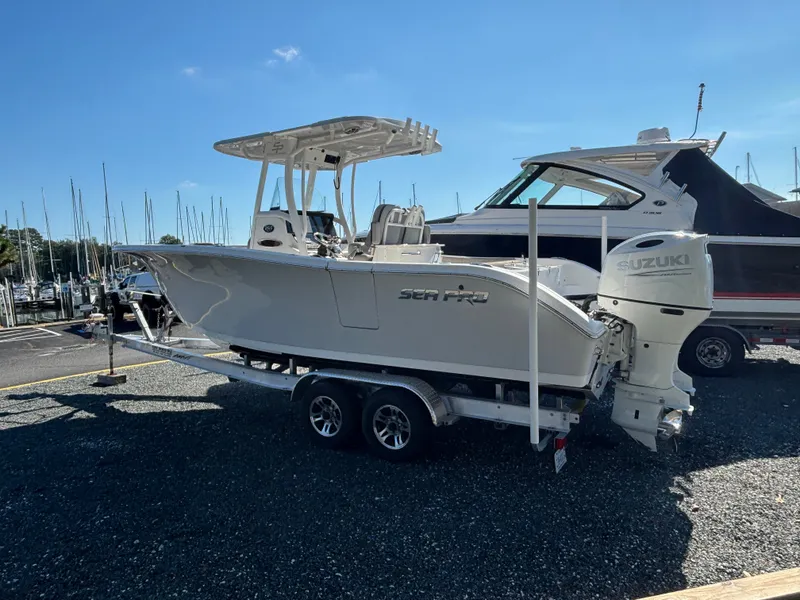 Slide: The Image of A 2021 Sea Pro 259 DLX boat on a trailer, with Suzuki outboard motor, parked at a marina. - 4