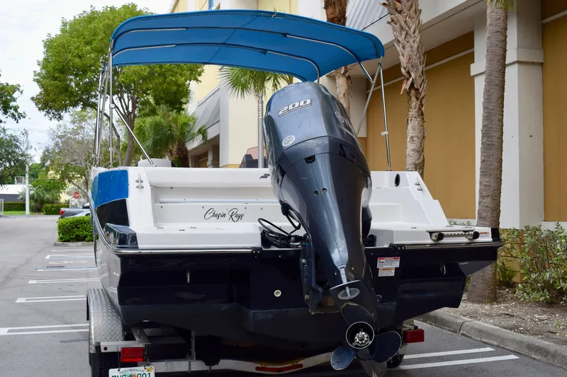 Slide: The Image of 2024 Starcraft SVX 231 OB DH boat with outboard motor and blue canopy in parking lot. - 3