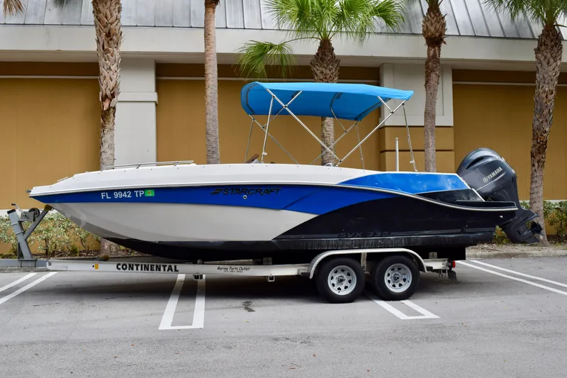 Slide: The Image of 2024 Starcraft SVX 231 OB DH boat on trailer with blue canopy and Yamaha outboard motor. - 1