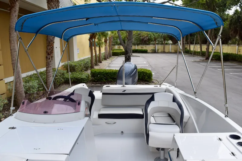 Slide: The Image of 2024 Starcraft SVX 231 OB DH boat with blue canopy and seating in a parking area. - 5
