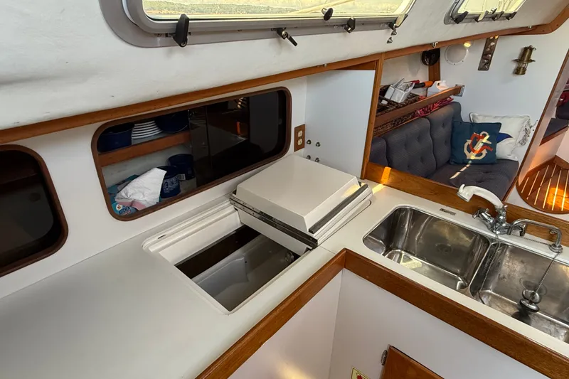 Slide: The Image of Interior of a 1994 J Boats J/120 yacht, featuring a compact kitchen with sink and storage. - 23