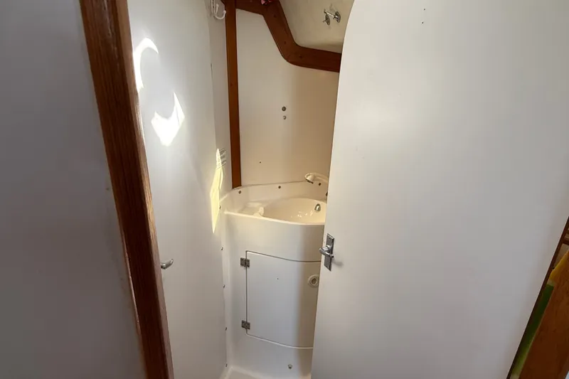 Slide: The Image of Compact bathroom in a 1994 J Boats J/120 sailboat, featuring a small sink and white interior. - 48