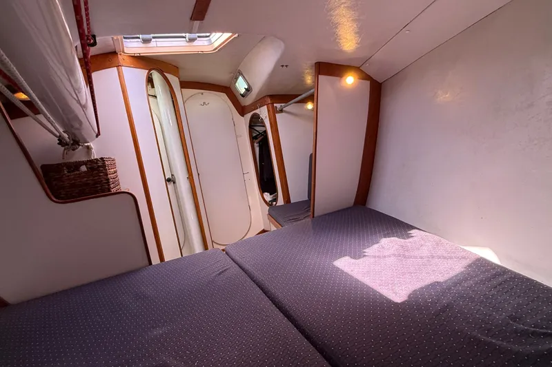 Slide: The Image of Interior cabin of a 1994 J Boats J/120 sailboat, featuring cozy bedding and wooden accents. - 43